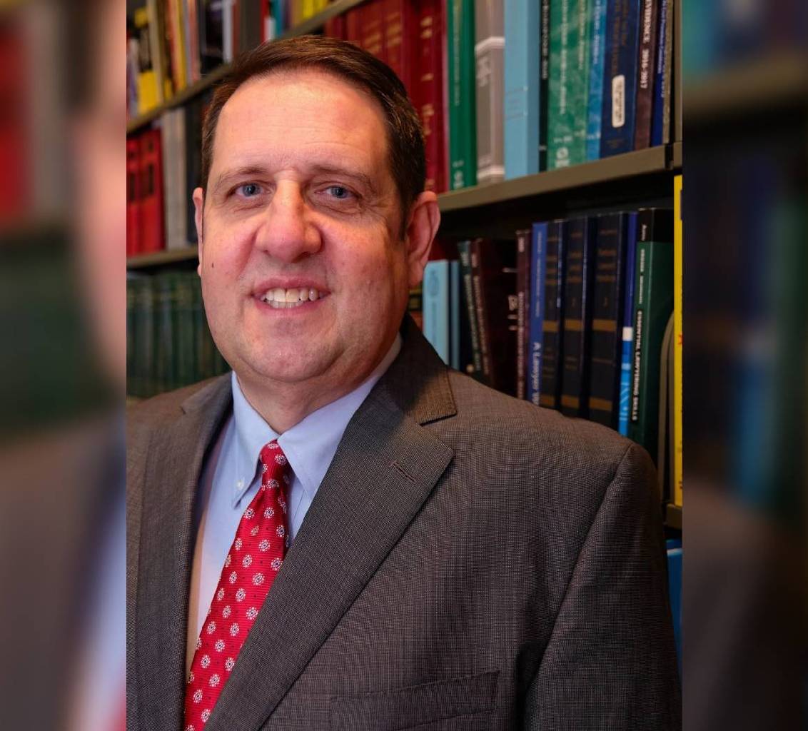 Professional man in suit smiling in a library setting.